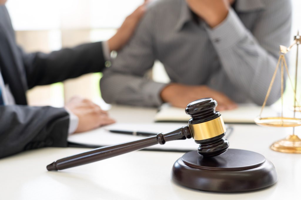 Attorney with client at desk with gavel in foreground