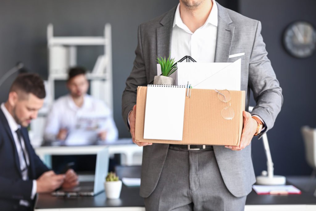 Empleado saliendo de la oficina con una caja de pertenencias personales