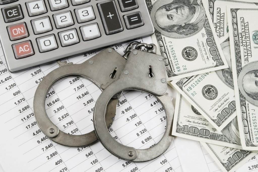 Calculator, handcuffs, cash, and financial statements