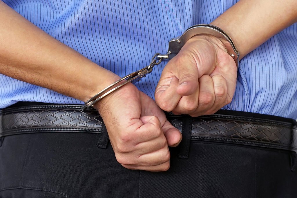 Man in business clothes with hands in cuffs