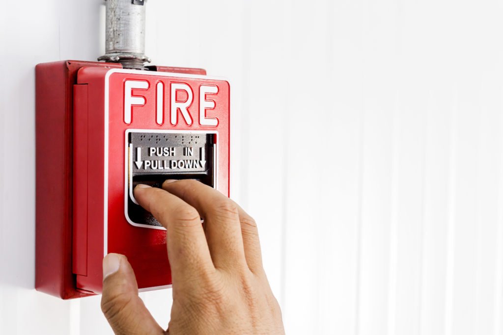 Man pulling down fire alarm to sound alarm