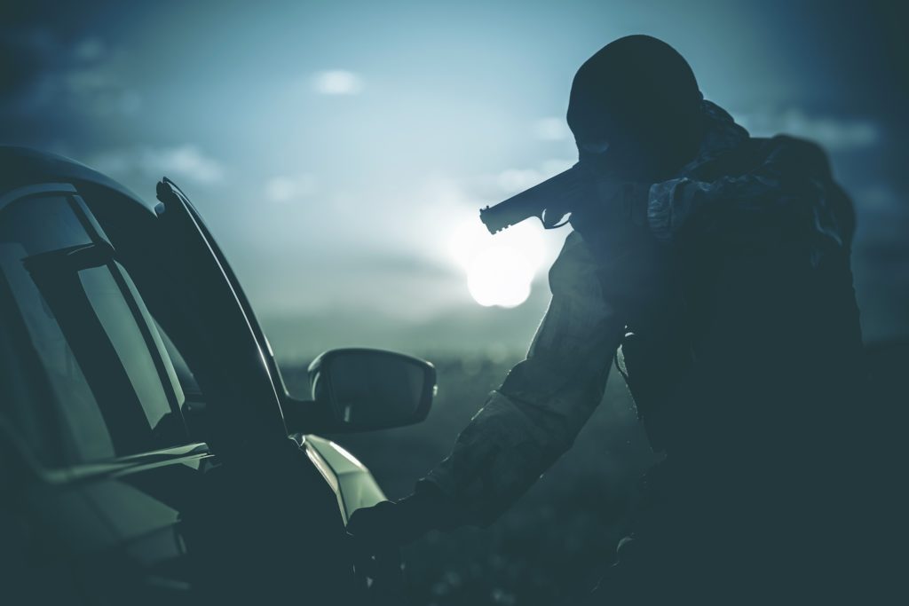Silhouette of man aiming gun into car as an example of illegal discharge of a firearm