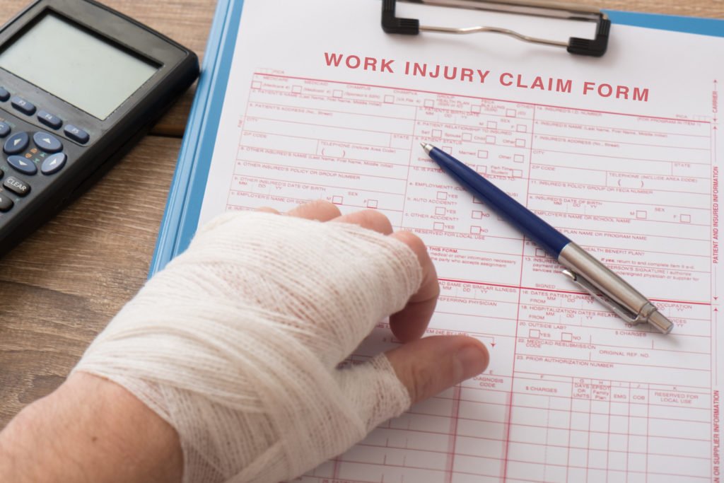 Hand wrapped in gauze filling out workers' comp claim form - if job doesn't have worker's comp you could be entitled to special damages