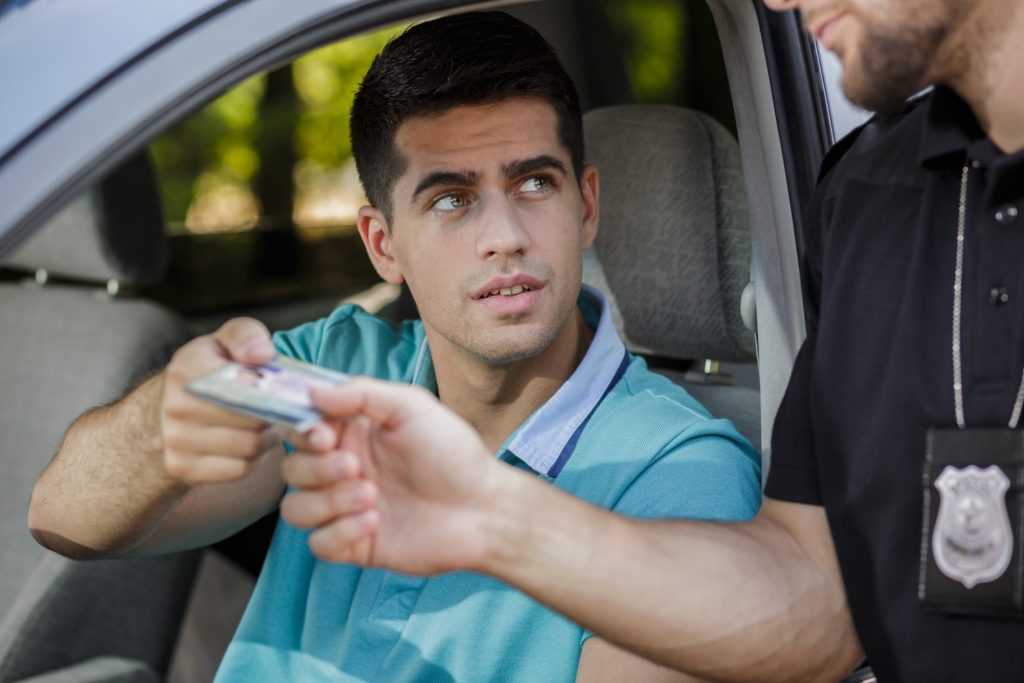 Conductor en una parada de tráfico entregando la licencia al policía