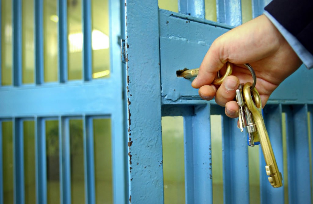 Closeup of hand with key unlocking jail door