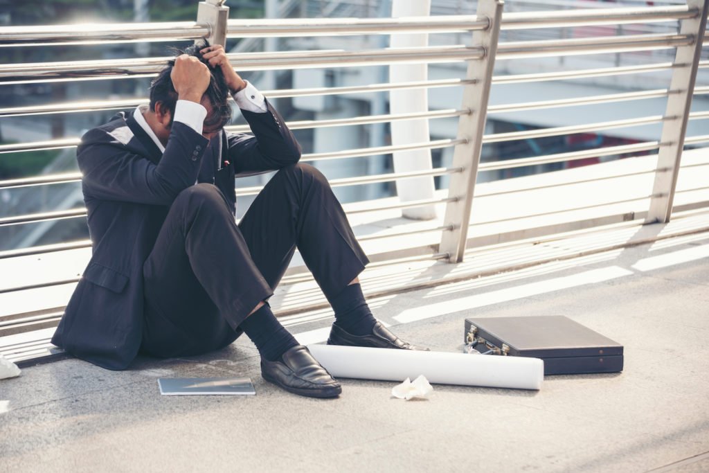Fired employee holding his head in dispair on floor