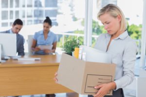 Fired worker carrying out box of belongings from office