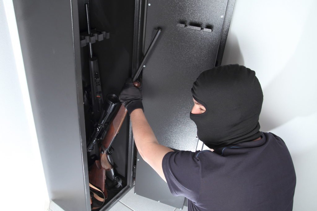 Ladrón robando arma de una caja fuerte como ejemplo de robo de armas de fuego según el Código Penal 247(d)(2) PC