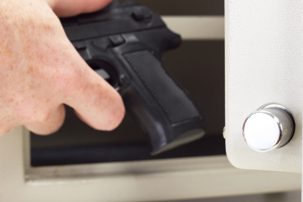 Close up of hand stealing gun out of safe