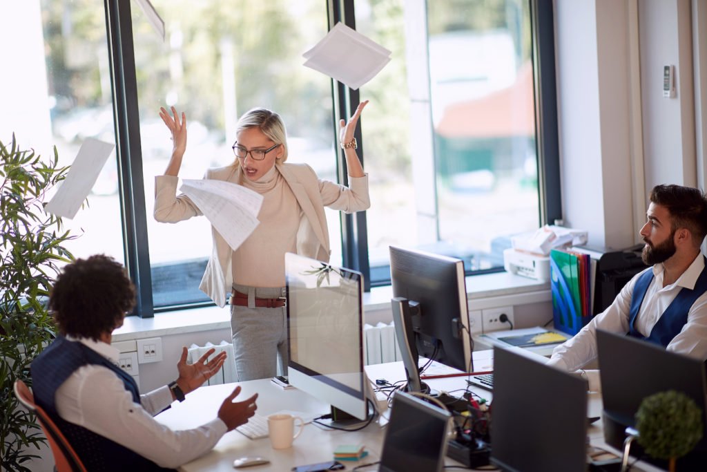Woman in office throwing up papers in anger
