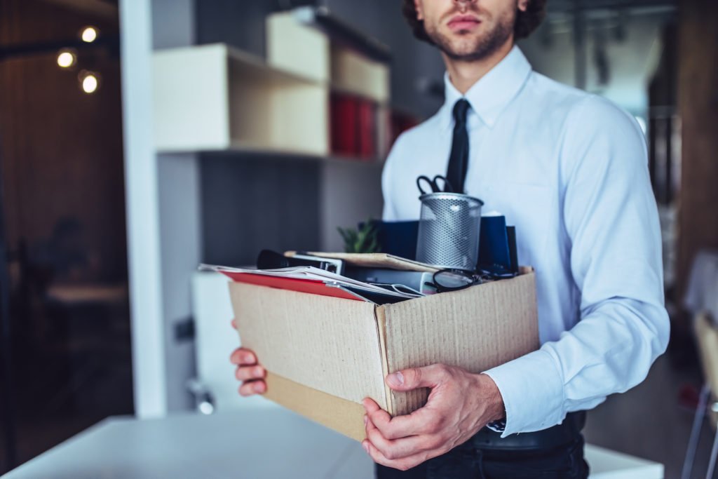 Fired employee carrying box of belongings out of office