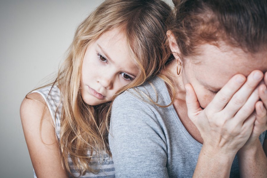 Mamá triste con su hija pequeña apoyándose en ella