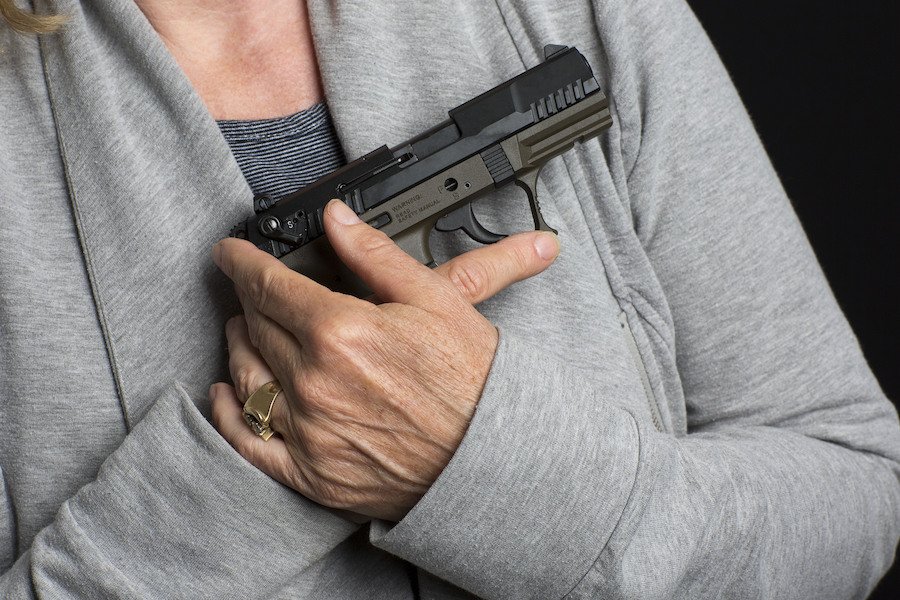 Closeup of woman holding gun about to violate PC 189. 