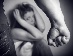 Girl cowering in corner with a man's fist in the foreground