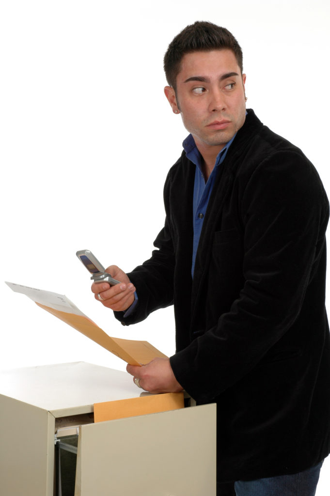 Man taking out files and photographing them while looking over his shoulder