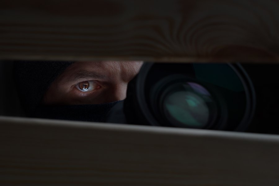 Hidden man with camera presumably taking naked photos of a neighbor