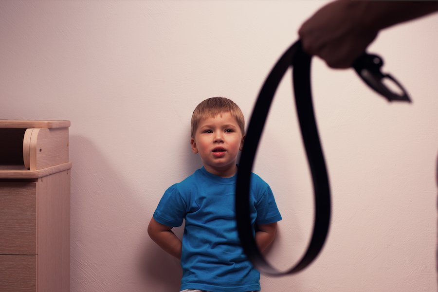 Niño contra mientras la mano del padre sostiene el cinturón - La ley de Nevada prohíbe el abuso, la negligencia o el peligro para los niños