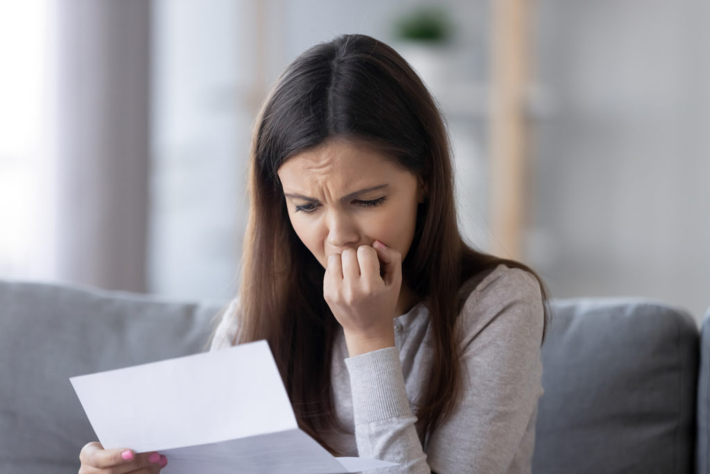 Mujer en el sofá leyendo una carta mirando angustiada