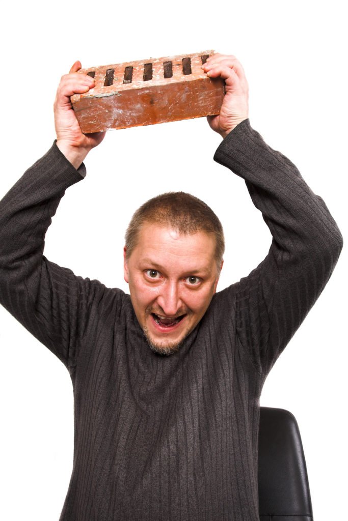Man menacing by holding a brick in a throwing position