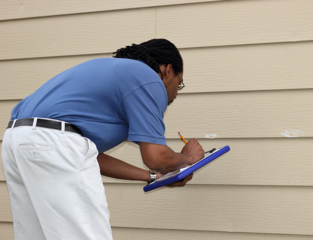 Insurance adjuster looking at property damage on house