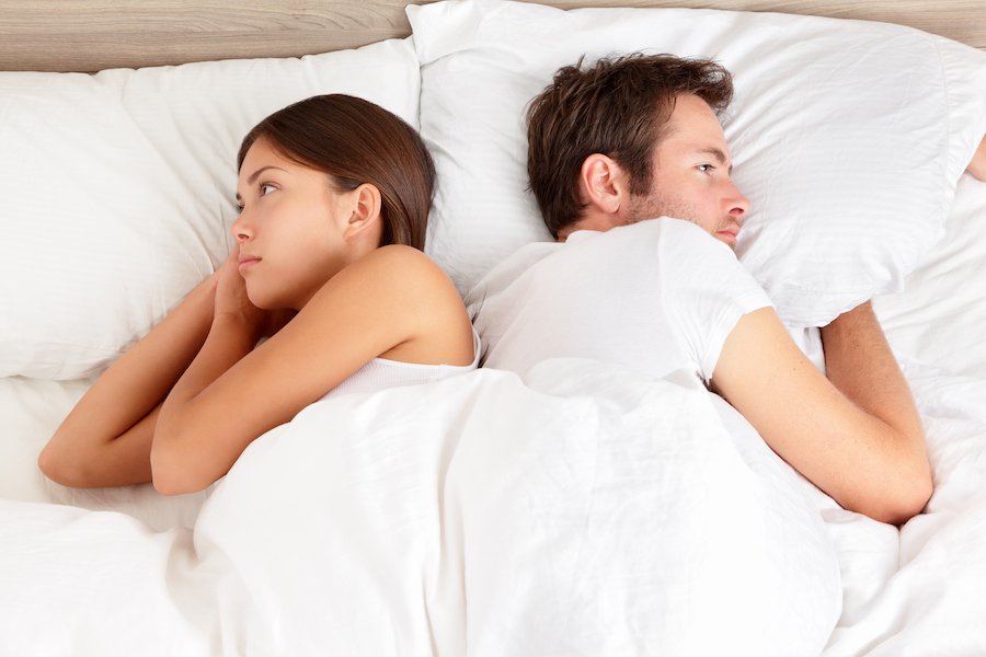 Man and woman in bed facing away from each other