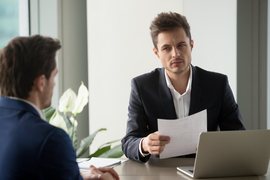 Empleado de CDLE mirando sospechosamente a un reclamante de seguro de desempleo