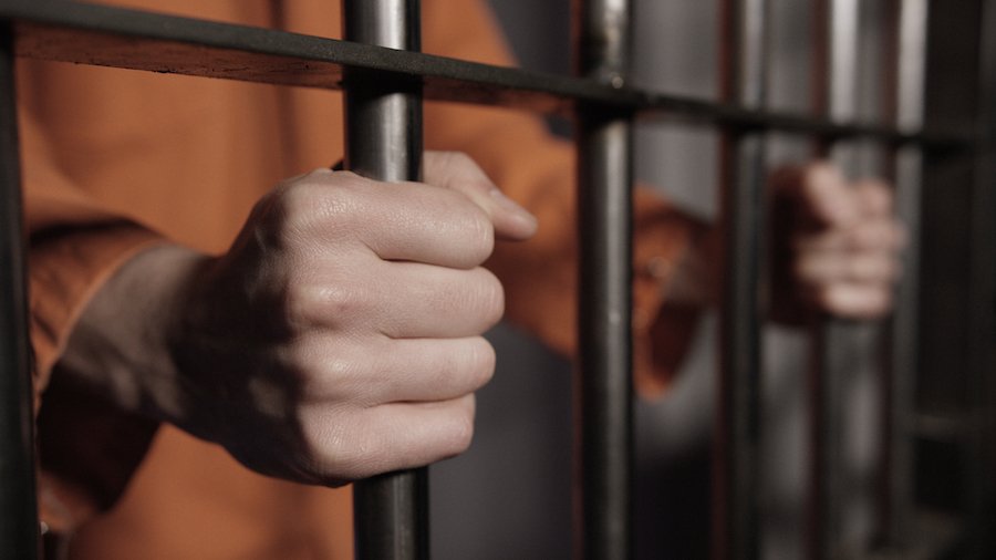 Mano de un preso sosteniendo barras de celda - El Código de Vehículos 23550 hace que el DUI de la cuarta vez sea un delito castigable con prisión
