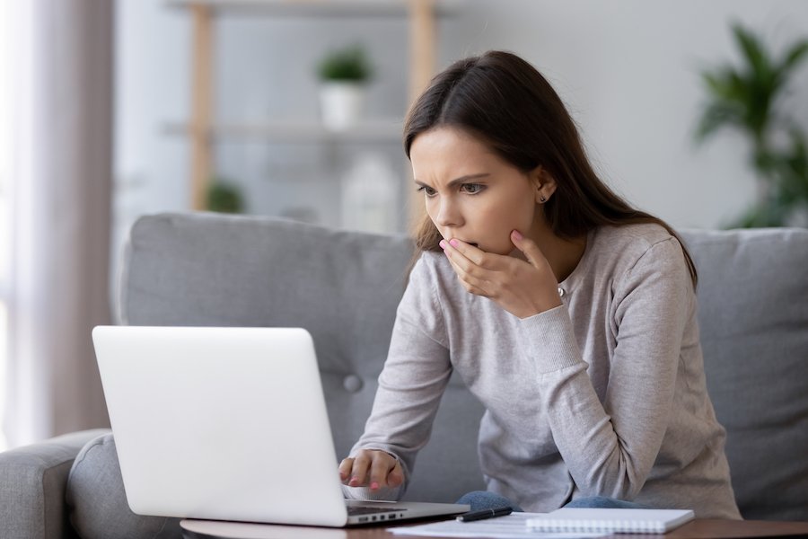 Distraught woman looking at computer after being extorted.