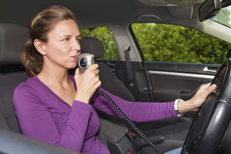 Woman in car blowing into breathalyzer