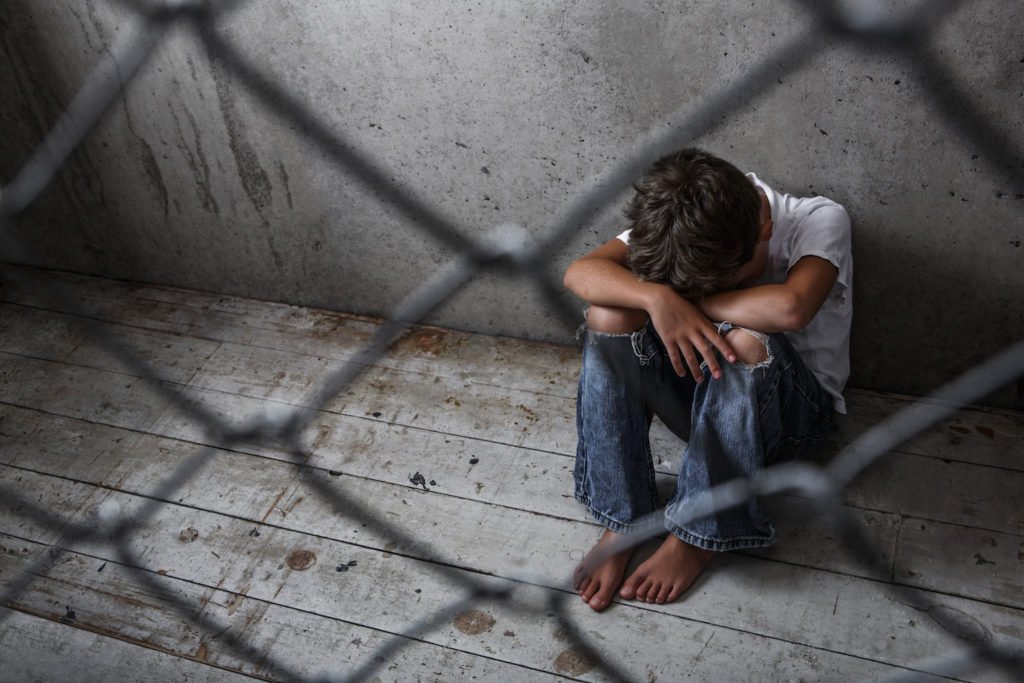 Young person crouching in a detention facility