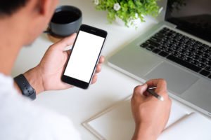 Employee holding a cell phone at his desk