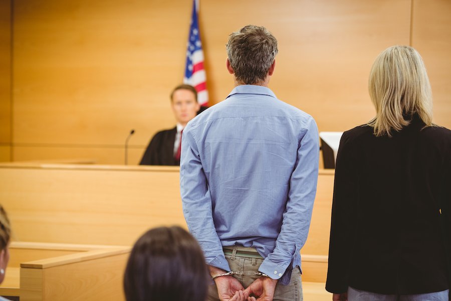 Man in handcuffs appearing with counsel before a judge