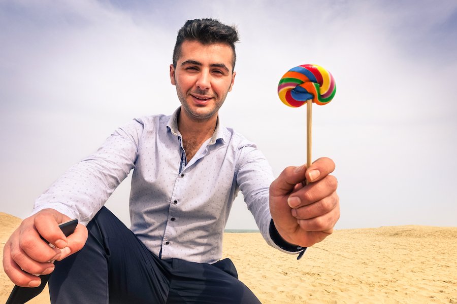 Man holding lollipop out to child behind the camera to illustrate solicitation of minor