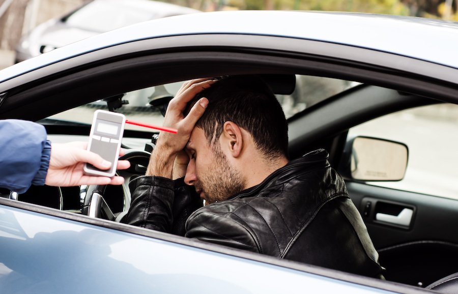 Frustrated driver behind whilee while police is holding a breathalyzer by him