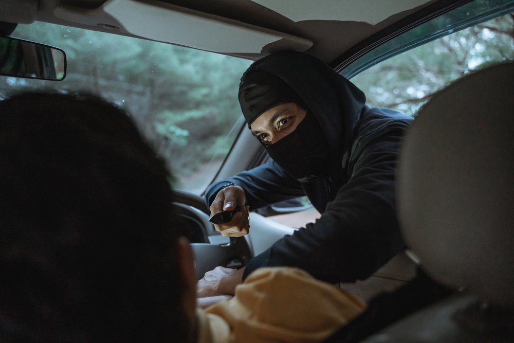 hombre enmascarado apuntando con un cuchillo al conductor