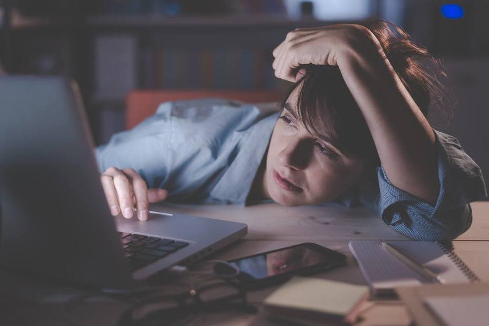 Tired employee at computer at night who may be entitled to OT under California overtime law for putting in late hours
