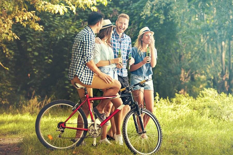 Person on bike with friends holding beers