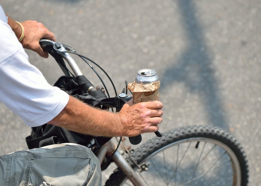 Close up of hand on bike handlebar holding a beer can