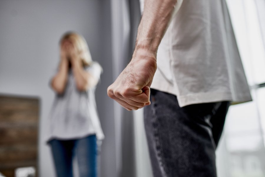 Man holding fist near woman looking distraught