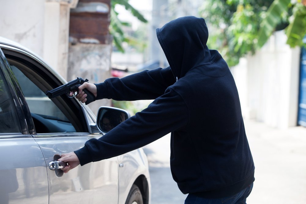 hombre apuntando con una pistola al conductor