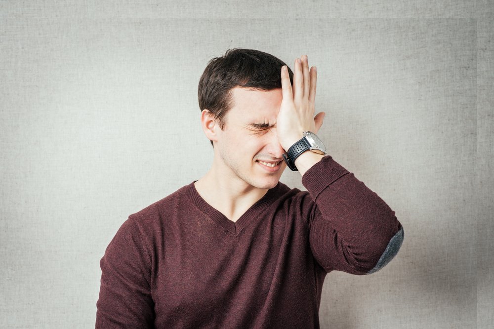 Man with hand over face with an expression of exasperation