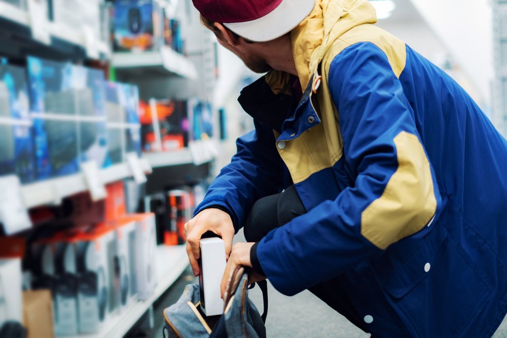 man stealing an item and putting it in his bag