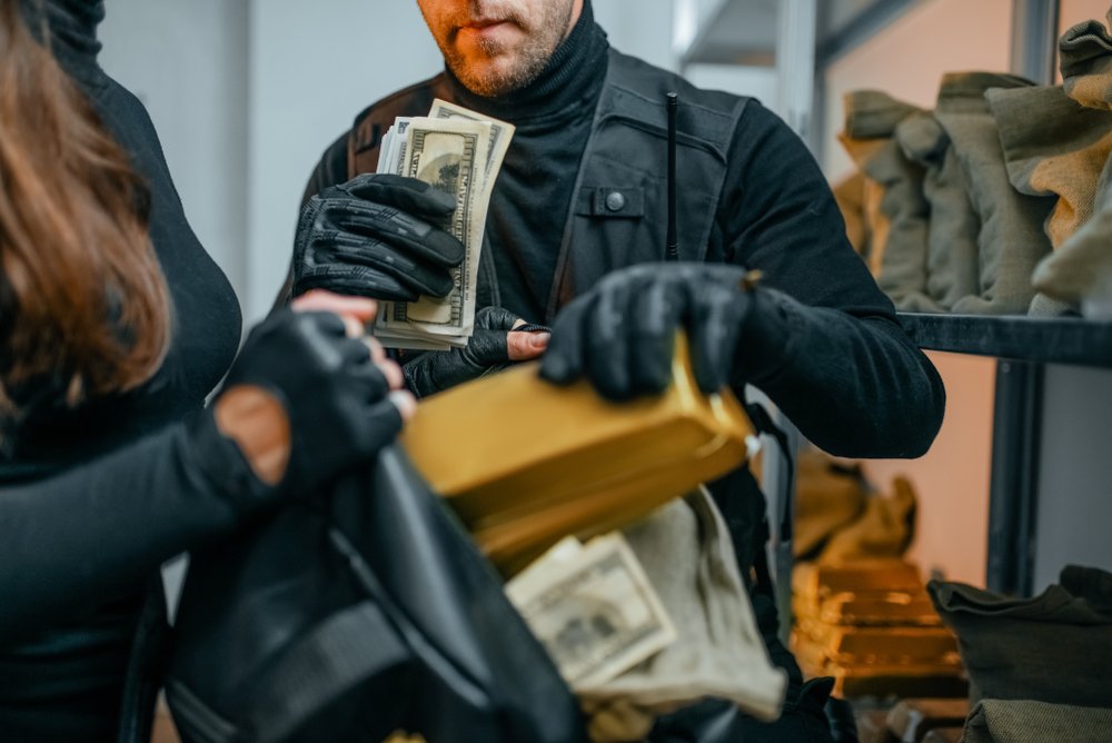 Los ladrones de bancos metiendo dinero en su bolsa: el Código Penal 213 PC establece las penas por robo en California.