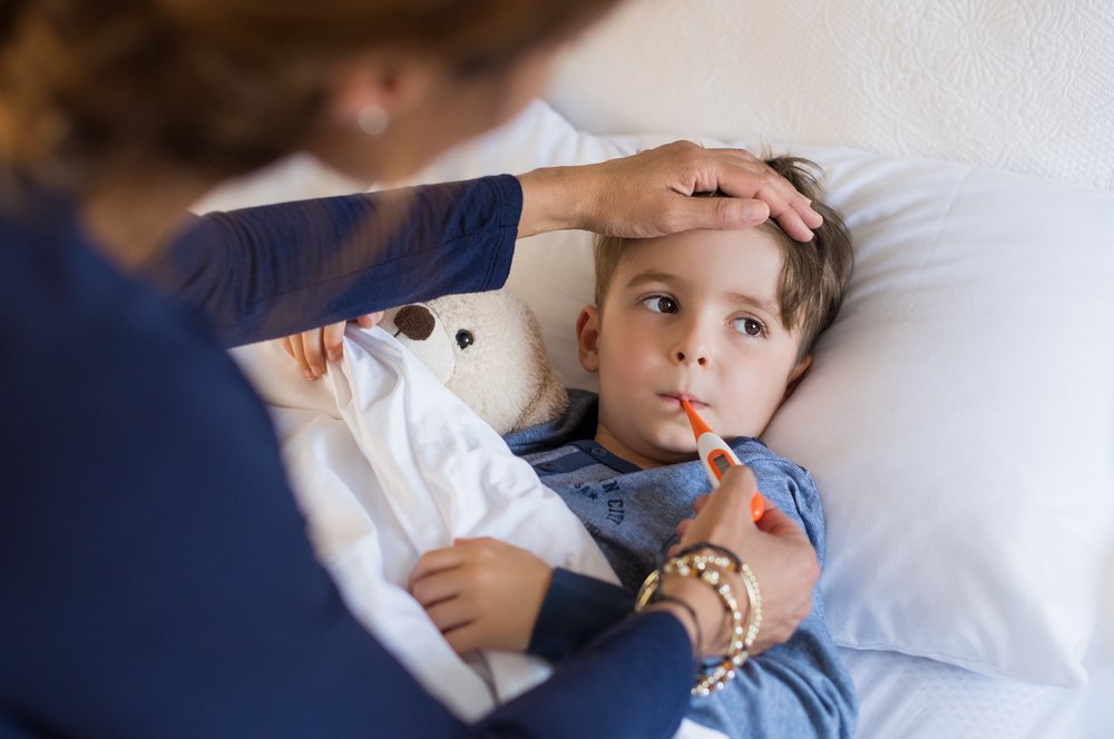 Mother taking the temperature of her child in bed.