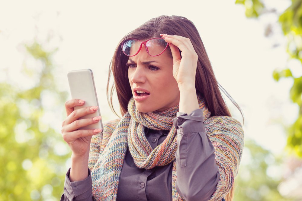 Woman shocked by what she is reading on her smartphone.