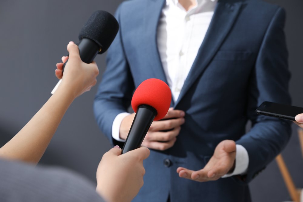 Hombre respondiendo preguntas de reporteros.