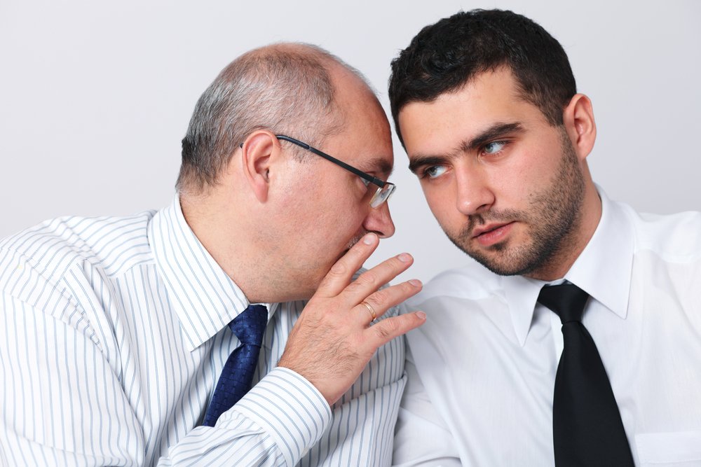 Man speaking with another man in private.