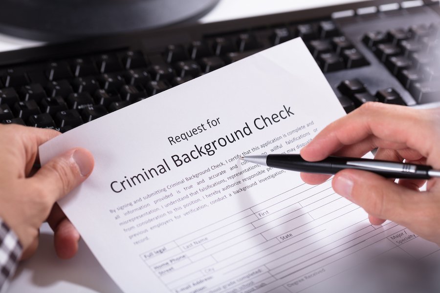 Primer plano de la mano de una persona llenando un formulario de verificación de antecedentes criminales