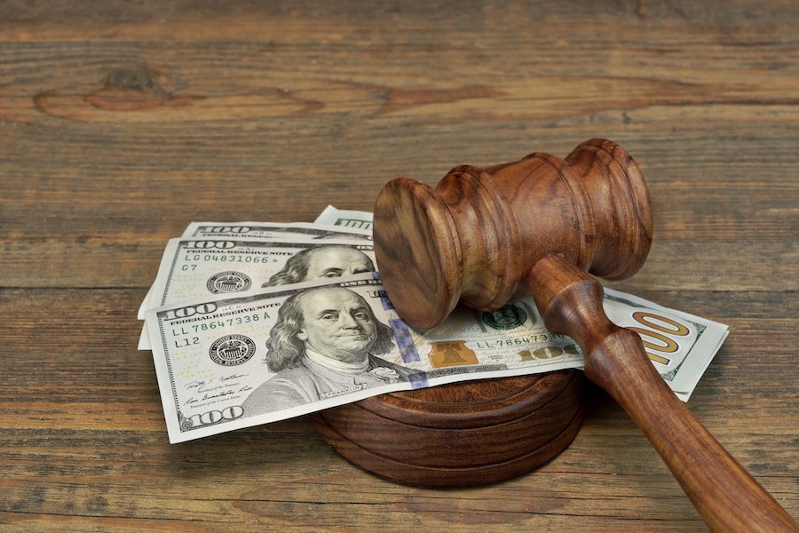 stack of $100 bills under a judge's gavel