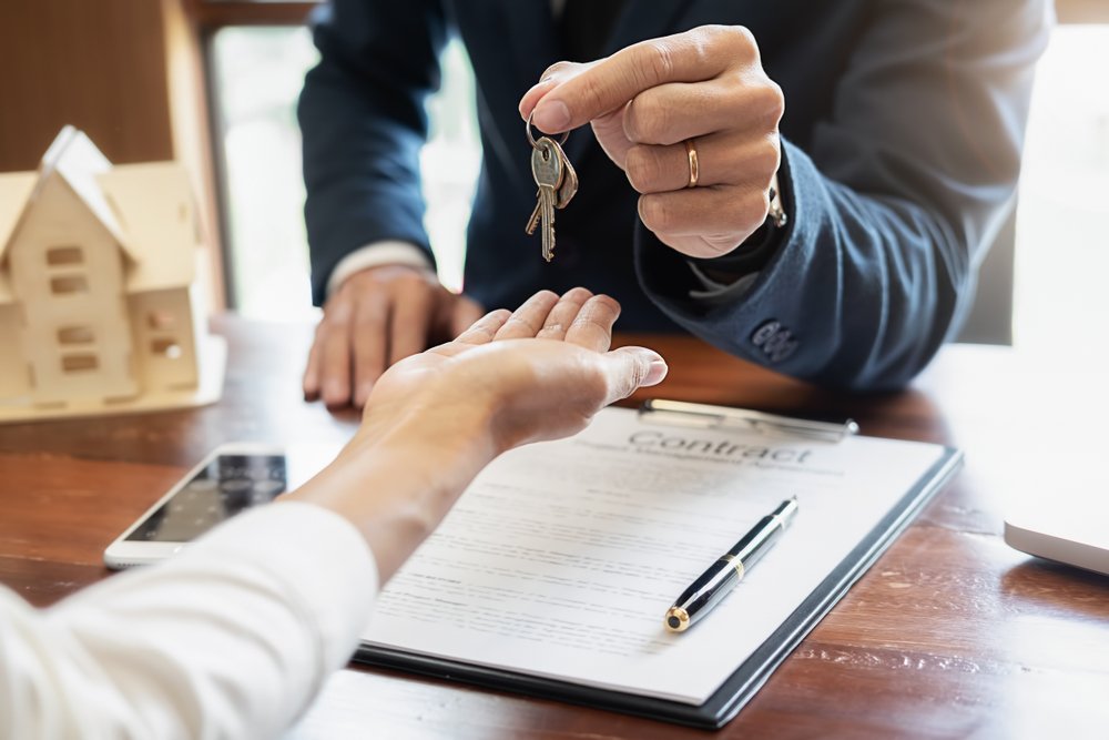 Person handing keys over to another person.